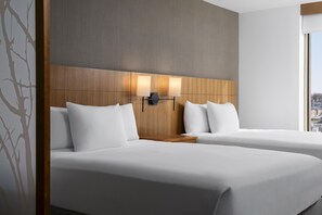 A hotel room with two beds, a wooden headboard, and a city view.
