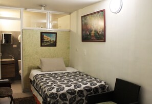 Een slaapkamer met een bed, een stoel, een bureau en een badkamer.