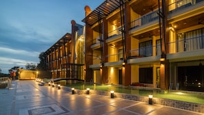 Un hotel de varios pisos con piscina, iluminación exterior y balcones.