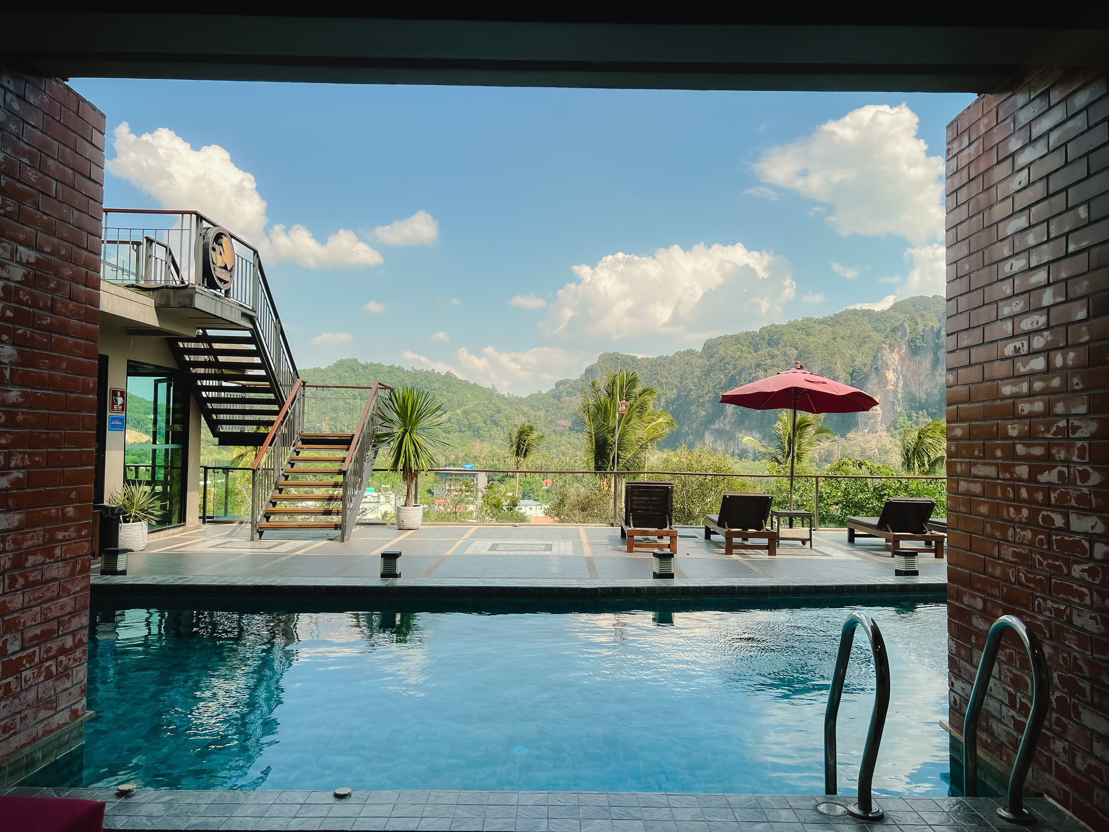 A pool area with a view of mountains, a staircase, and lounge chairs.