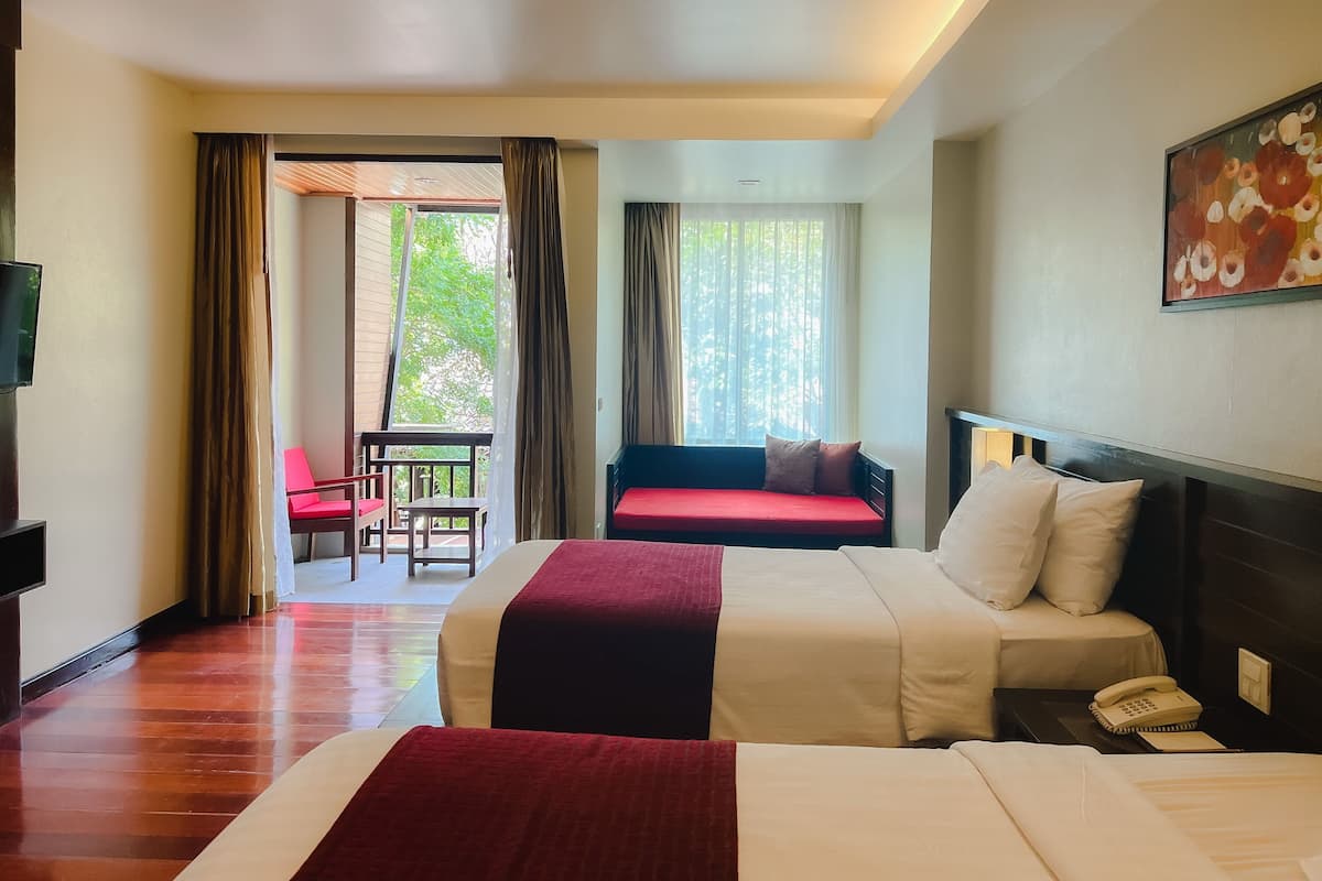 A hotel room with two beds, a TV, a phone, and a painting on the wall.
