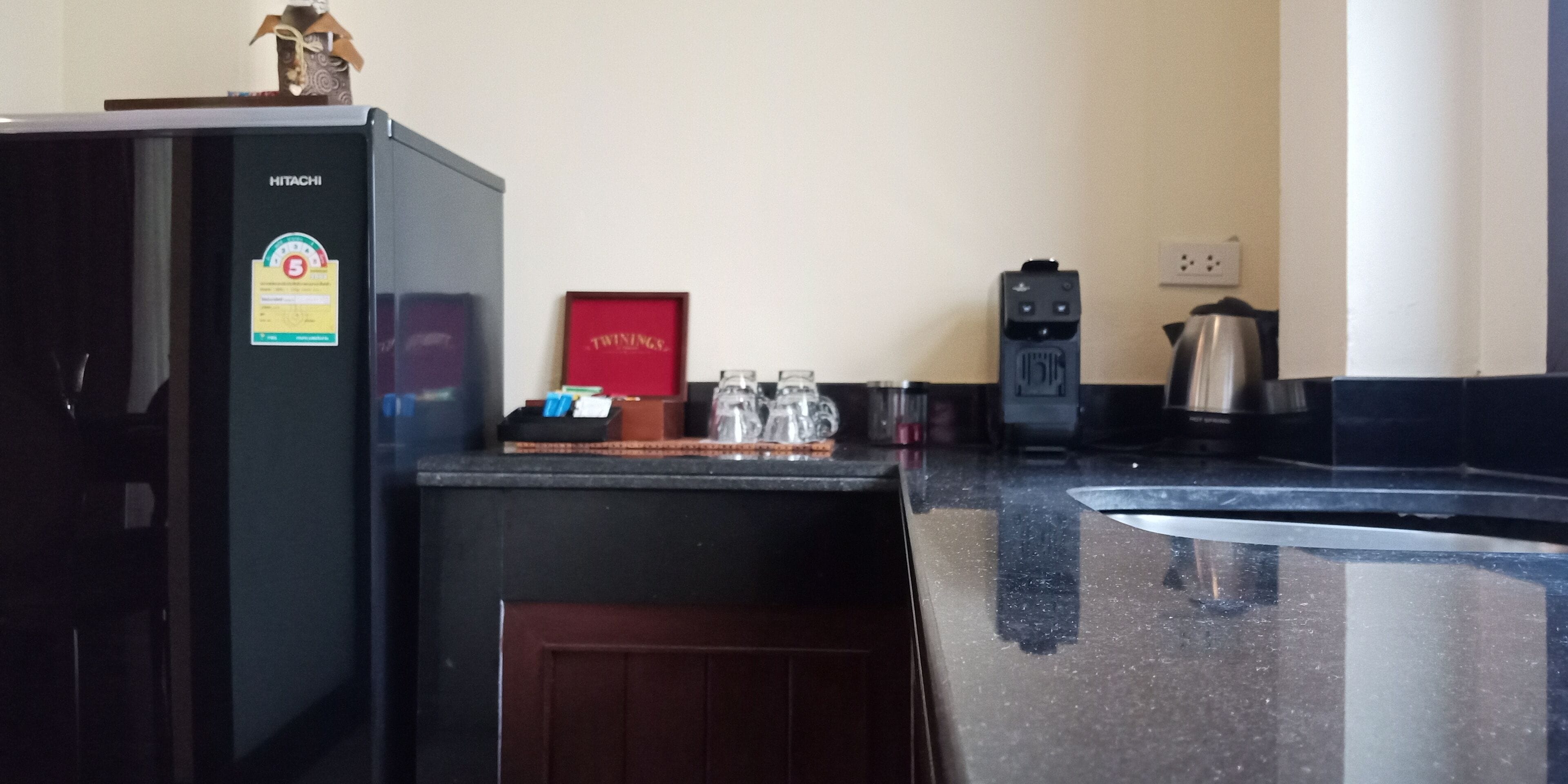 A kitchen with a black refrigerator, a coffee maker, and a microwave.