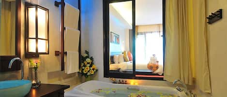 Un baño moderno con bañera, lavamanos y un espejo grande.