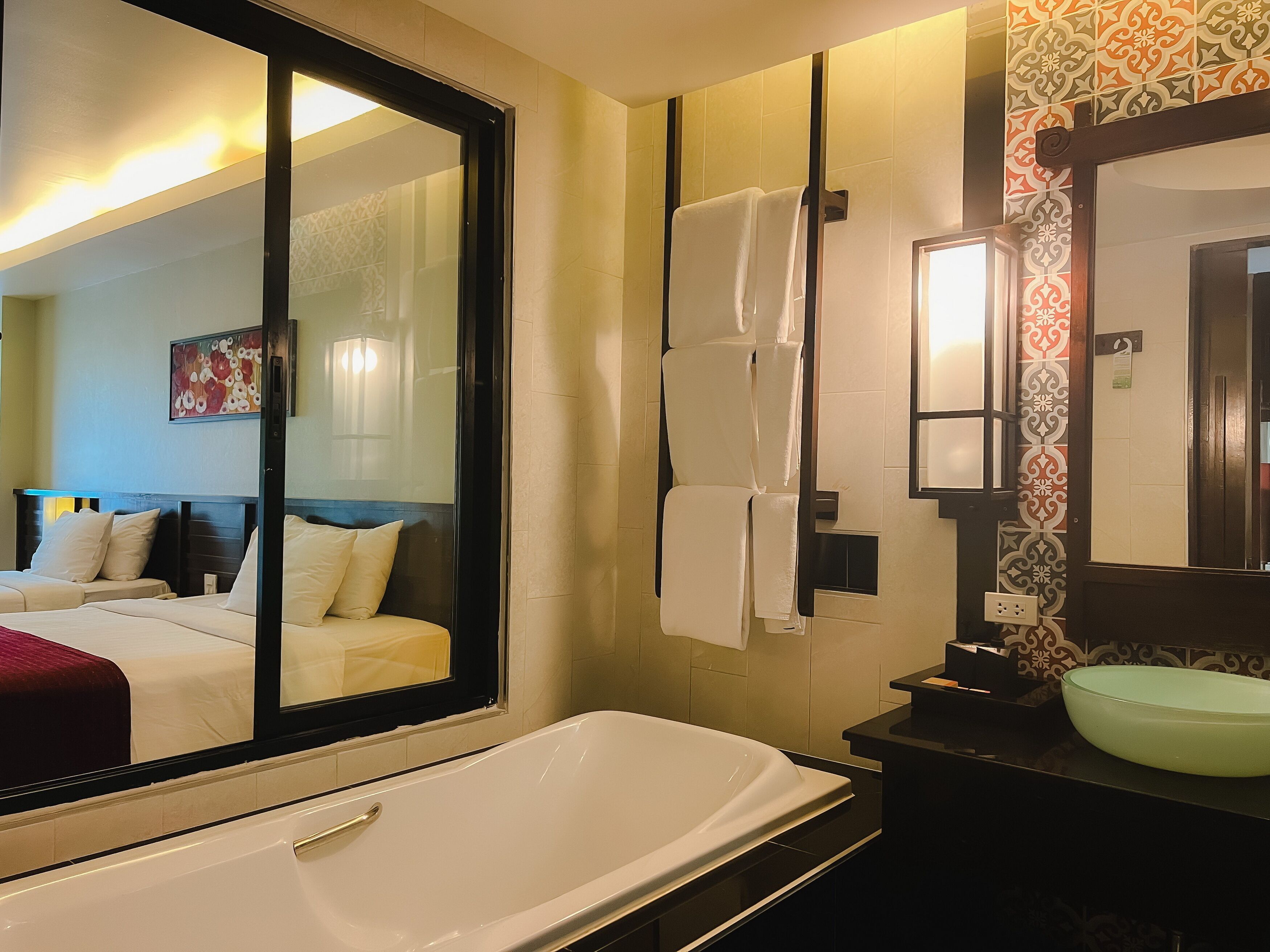 A modern bathroom with a large mirror, a bathtub, and a sink.