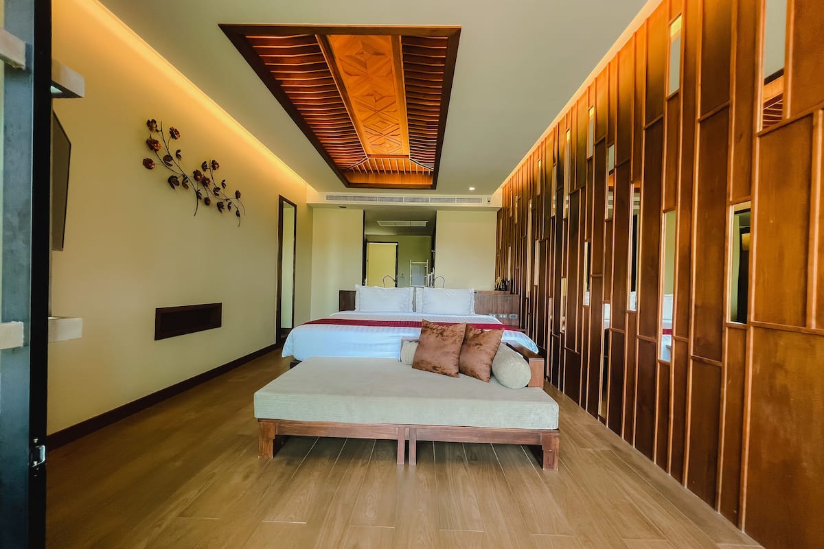 A modern hotel room with a large bed, wooden paneling, and a ceiling with a geometric design.