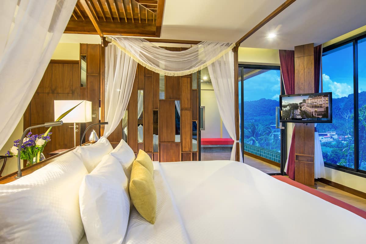 A bedroom with a large bed, a TV, and a view of a cityscape.