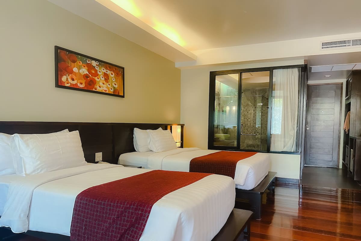 A hotel room with two beds, a large painting on the wall, and a sliding door leading to a bathroom.