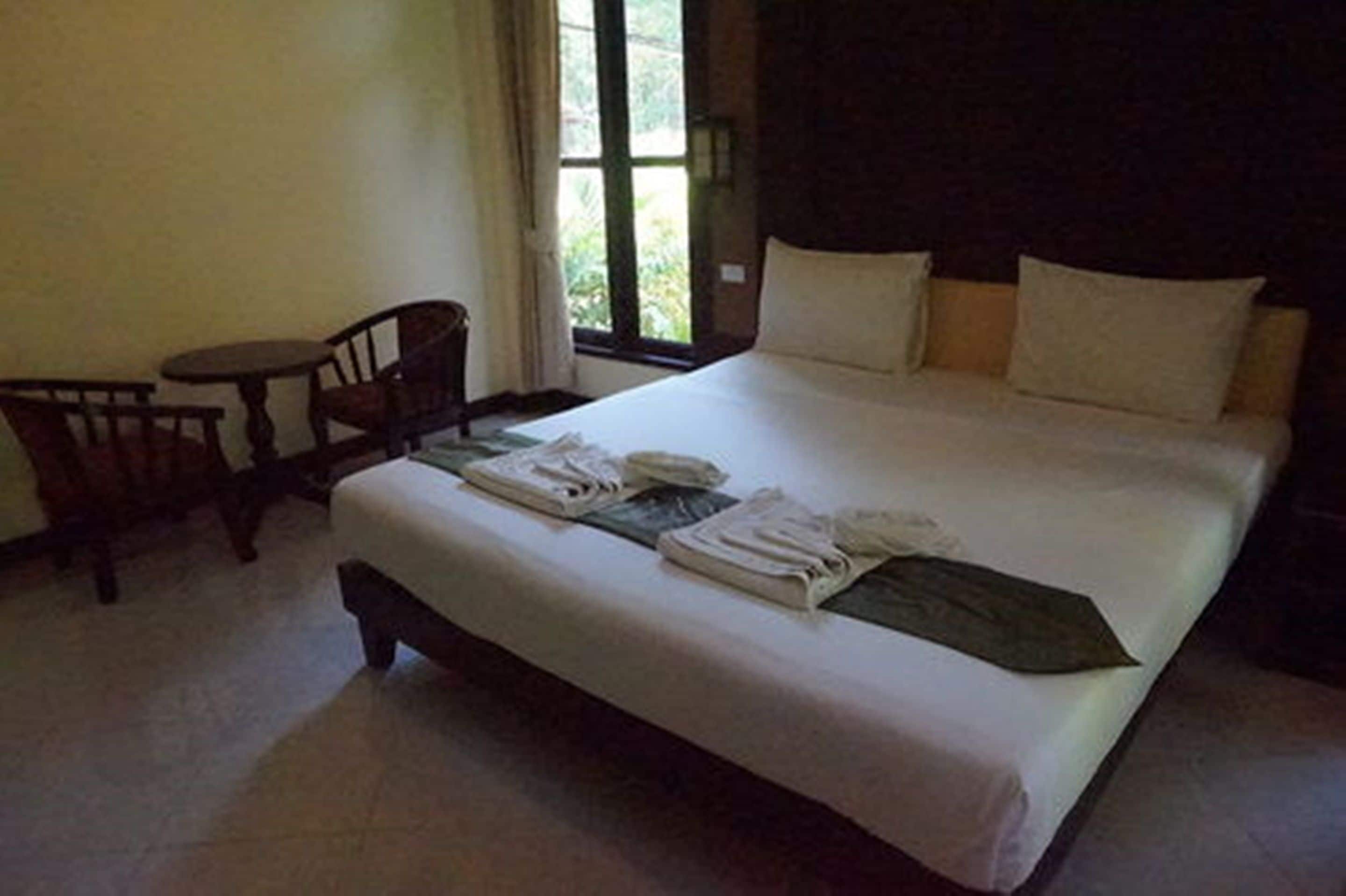 Een hotelkamer met een bed, een stoel en een tafeltje.