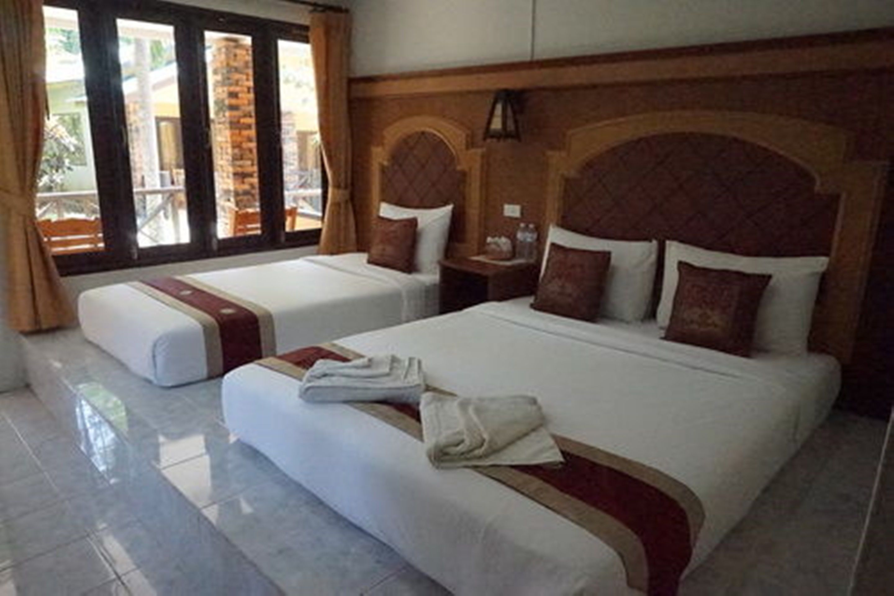A hotel room with two beds, a wooden headboard, and a balcony with a view.