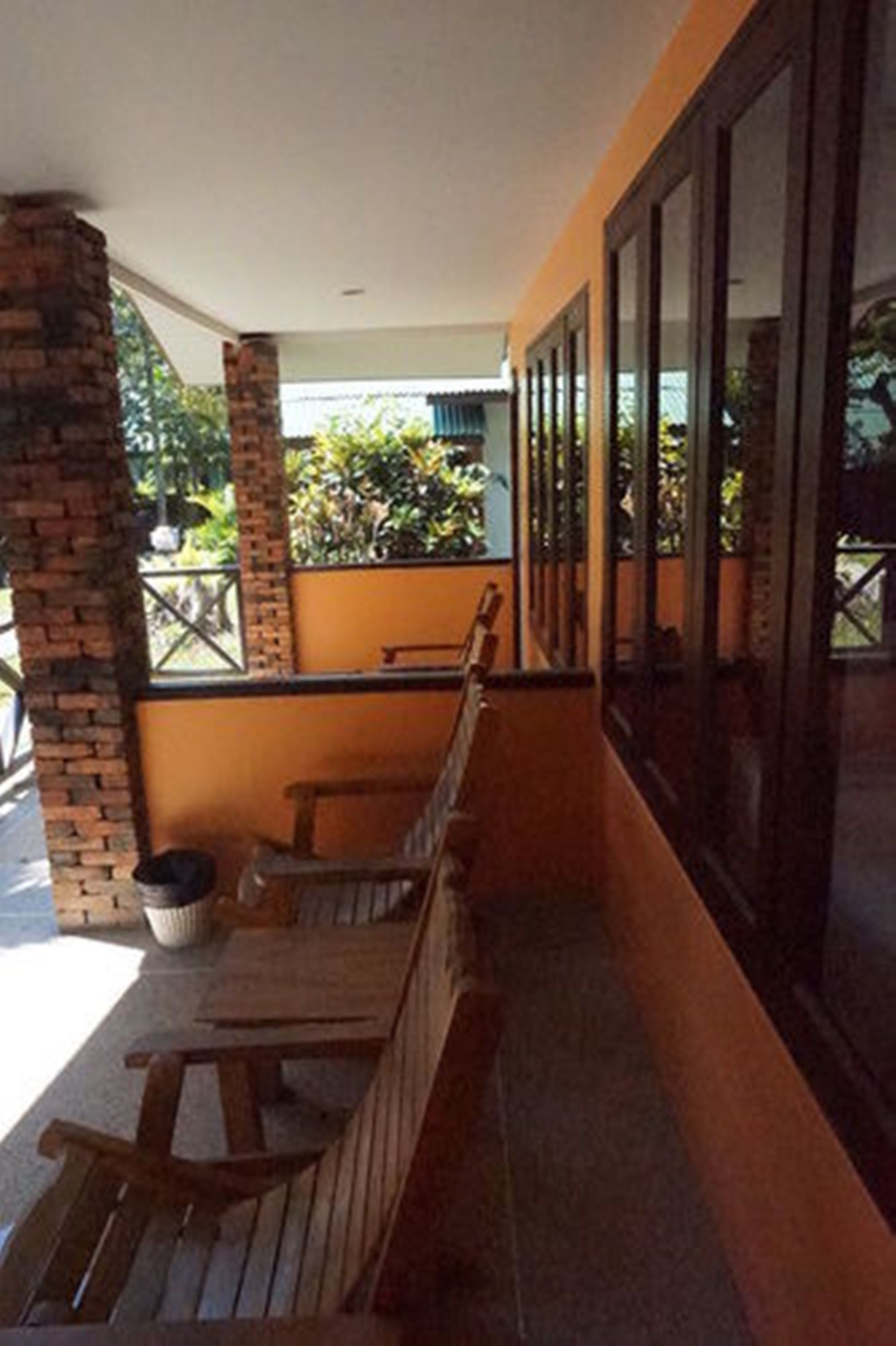 A covered outdoor seating area with wooden benches and a brick pillar.