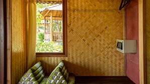 A room with a woven bamboo wall, a window with a view of greenery, and a wall-mounted electrical box. - Railay Garden View Resort (Krabi)
