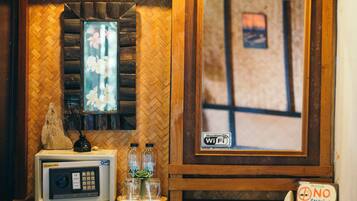 A room with a herringbone-patterned wall, a framed picture, a microwave, a small table with bottles and a flower, and a 'No Smoking' sign.