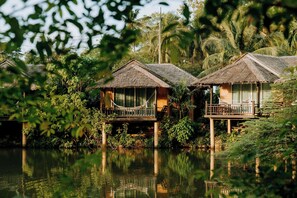 Overwater bungalows with thatched roofs, wooden balconies, and surrounded by lush greenery and water. - Ban Sainai Resort (Krabi)