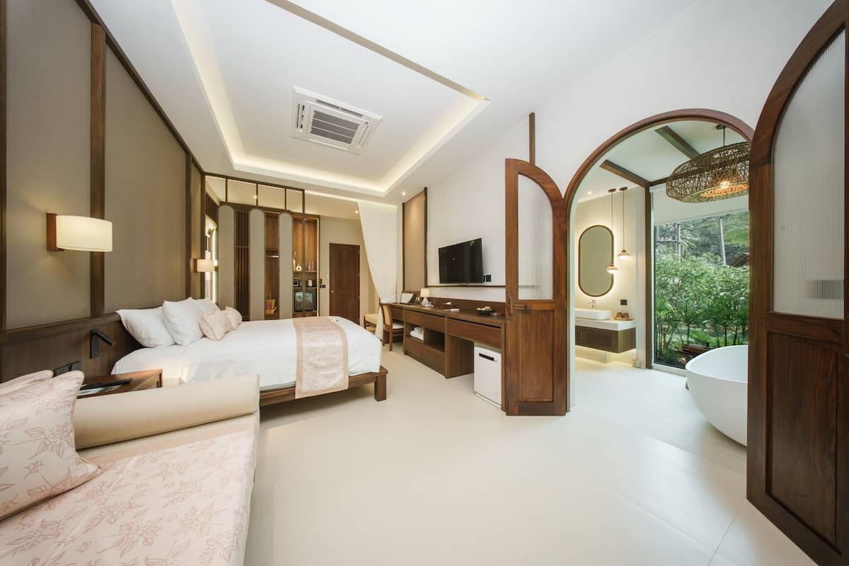 Una habitación de hotel moderna con cama, escritorio y baño.