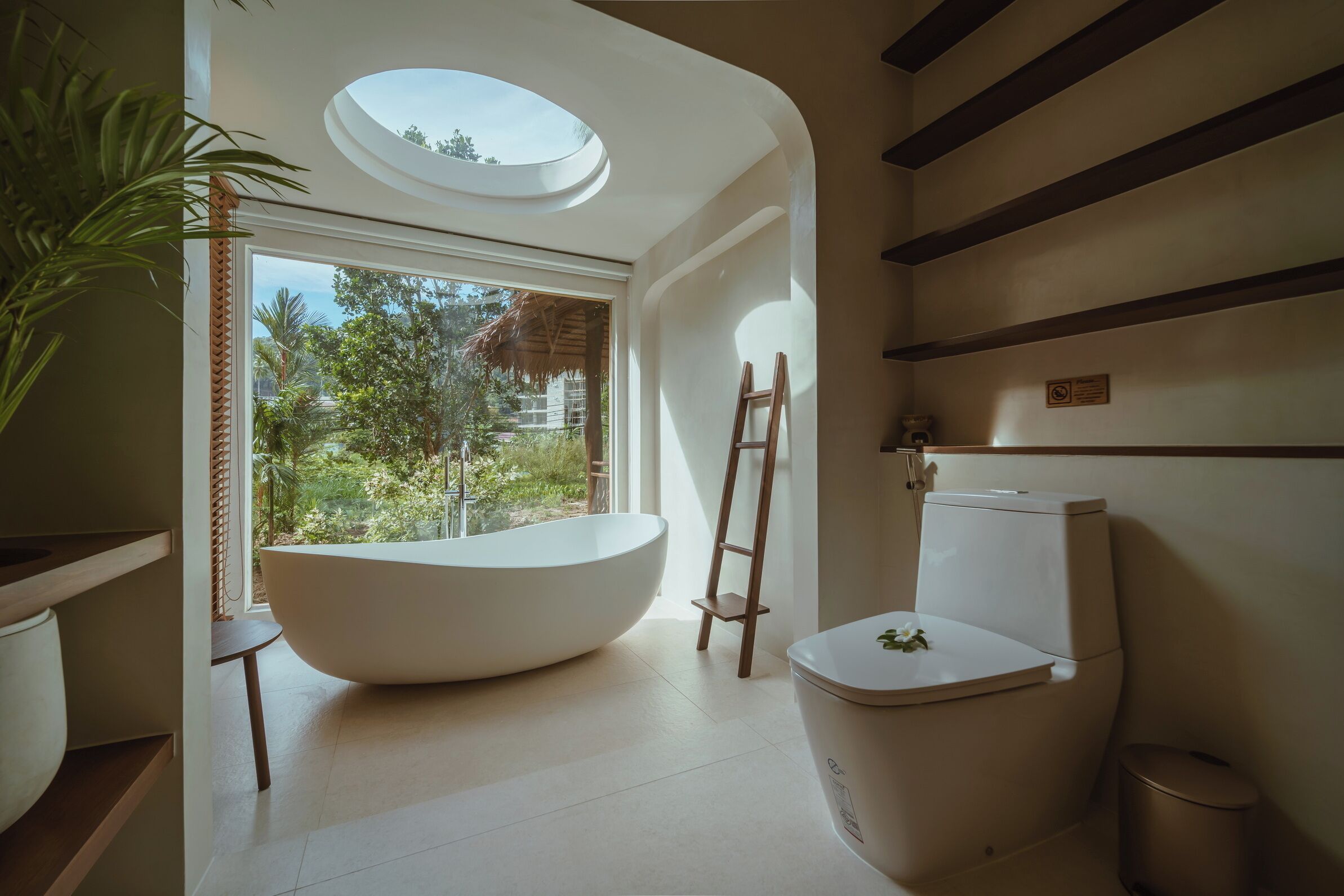A modern bathroom with a skylight, a freestanding bathtub, and a toilet.