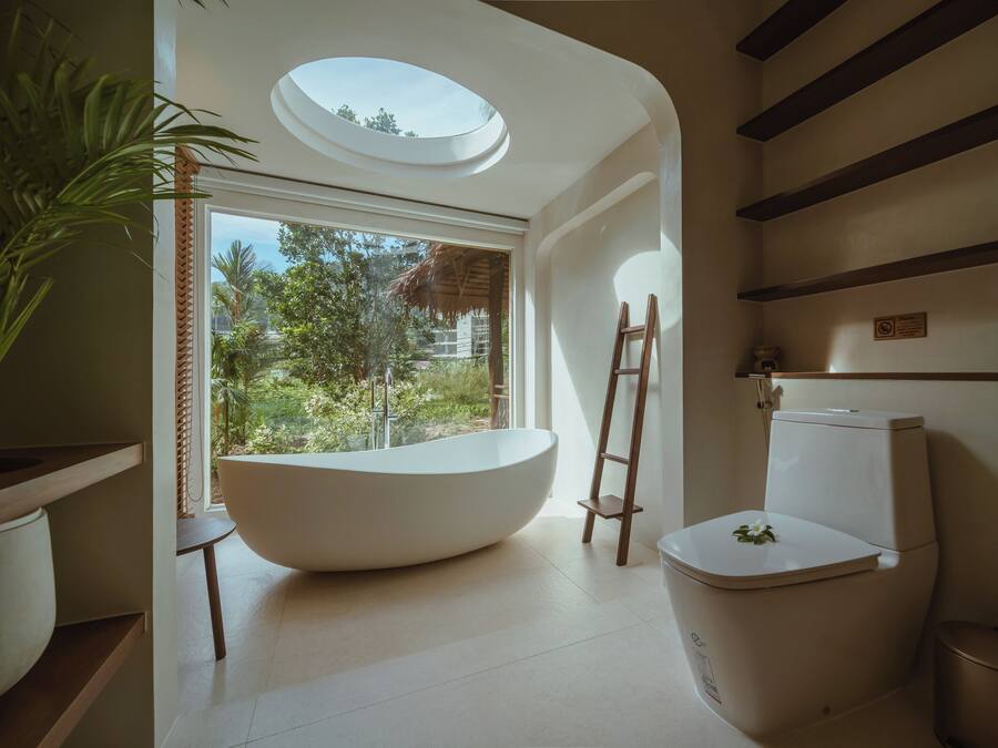 A modern bathroom with a skylight, a freestanding bathtub, and a toilet.