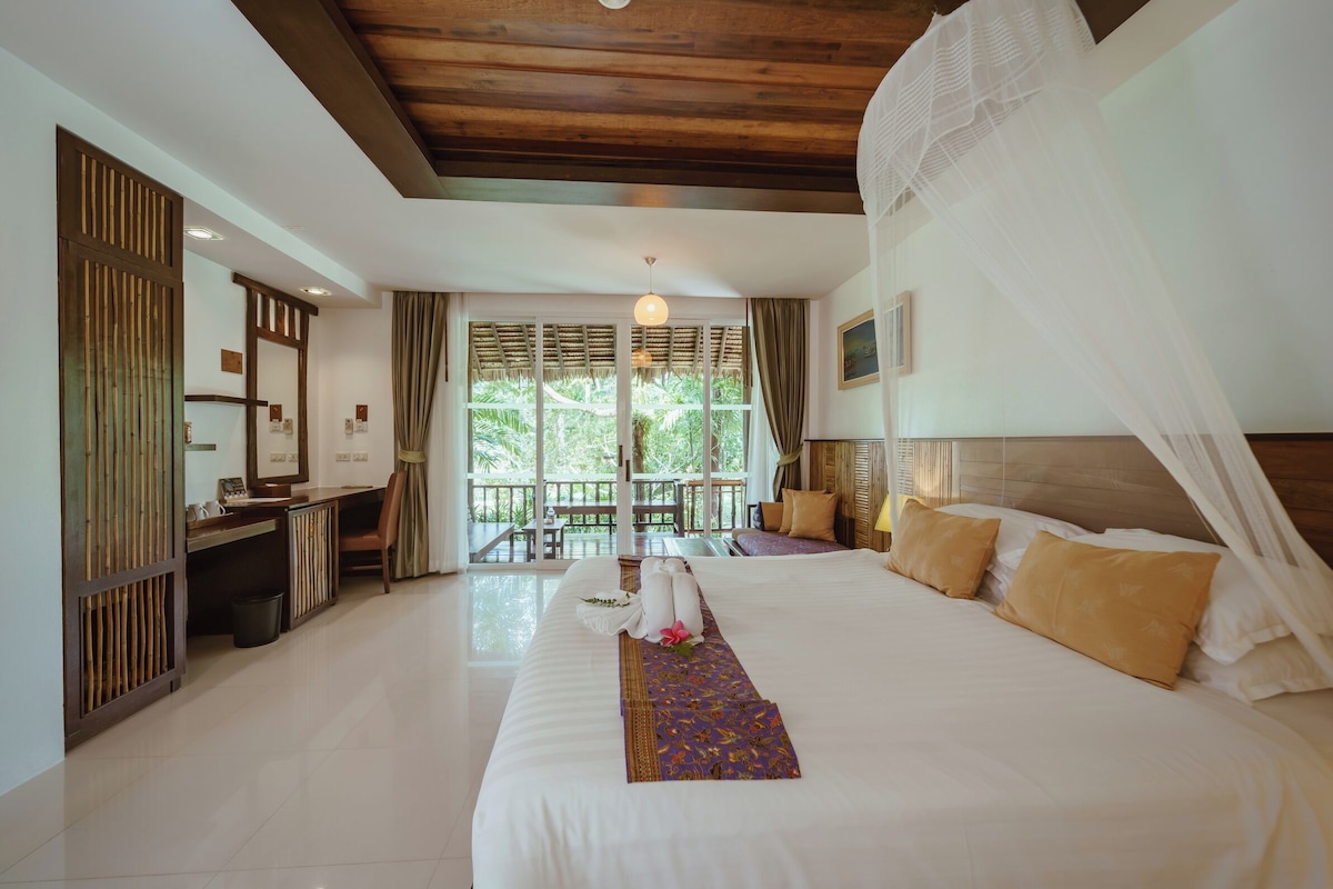A hotel room with a large bed, a desk, and a view of the outdoors.