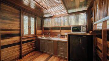 A wooden cabin interior with a kitchen area, including a sink, cabinets, and a refrigerator.