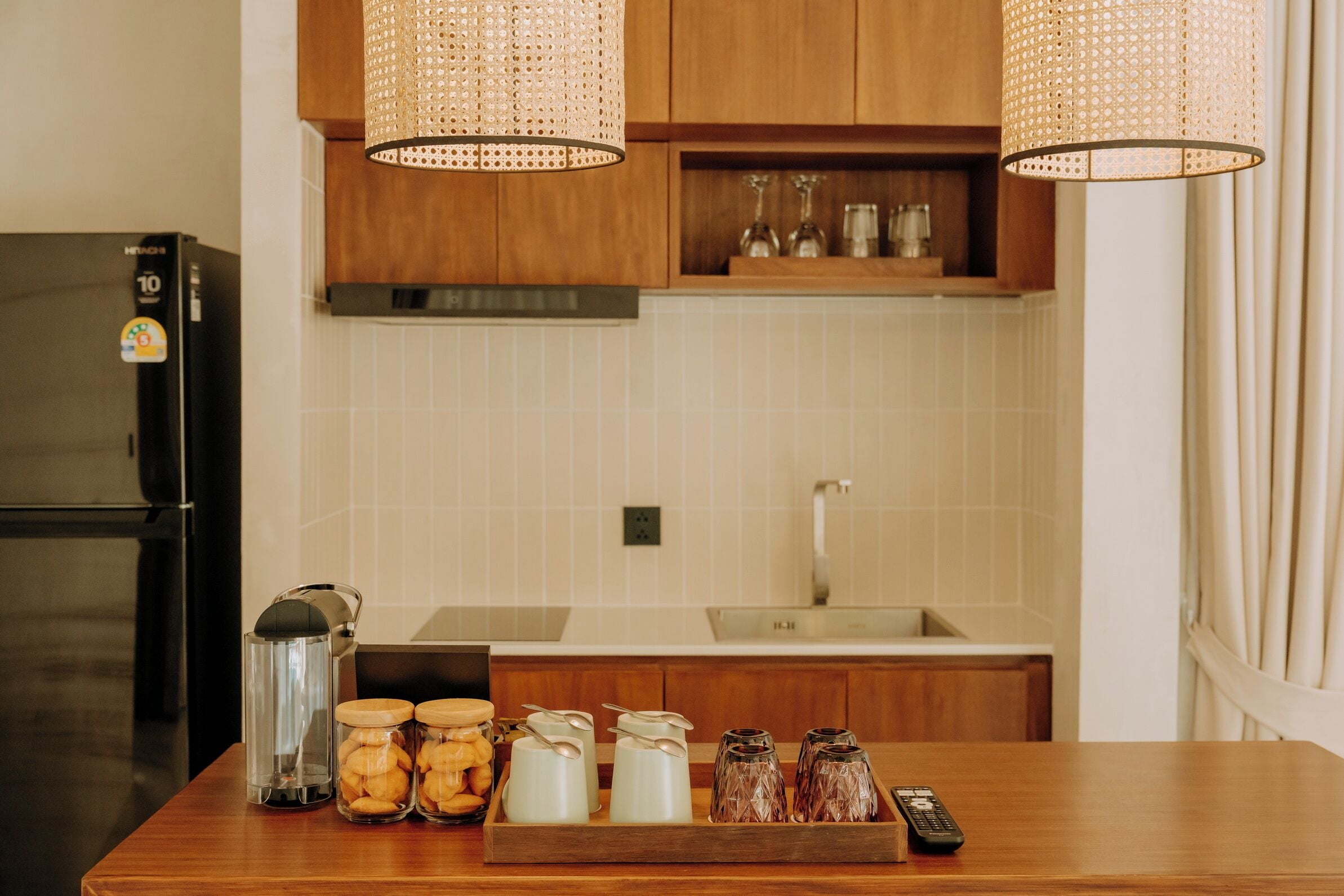 A kitchen with wooden cabinets, a stainless steel refrigerator, a coffee maker, and jars on the counter.