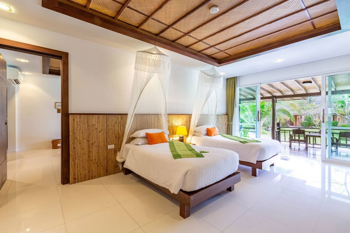 Un dormitorio con dos camas, techo de madera y vistas al exterior.