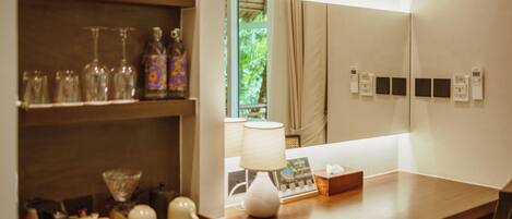 A hotel reception area with a wooden counter, a white lamp, and a window with curtains.