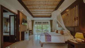 A spacious bedroom with a large bed, a bedside table with a lamp, and a TV mounted on the wall.