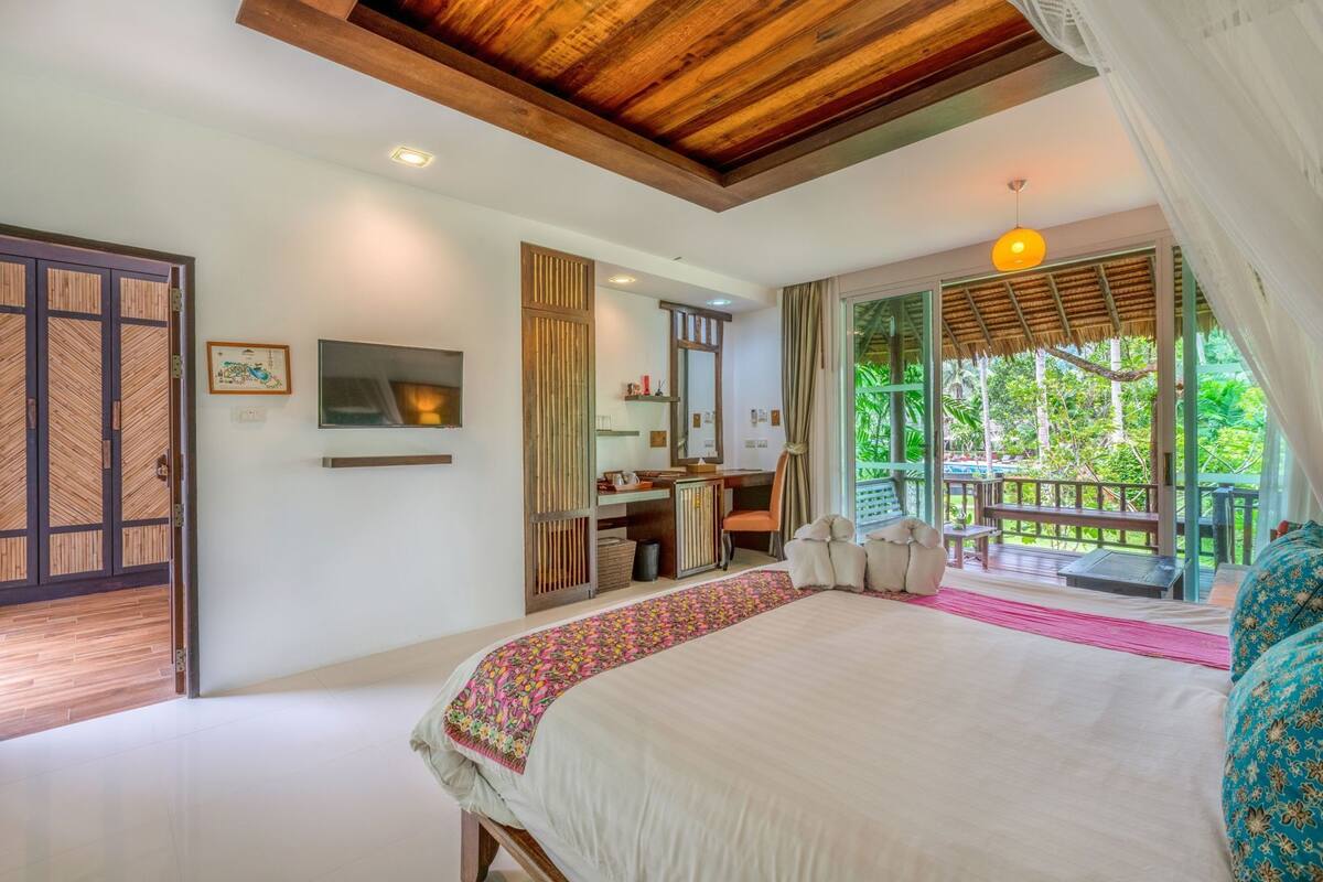 Un dormitorio con una cama grande, un escritorio, una silla y vistas al exterior.