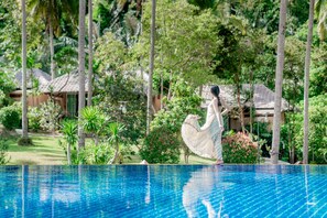 A swimming pool with a clear blue water surface, surrounded by lush greenery and palm trees. - Ban Sainai Resort (Krabi)