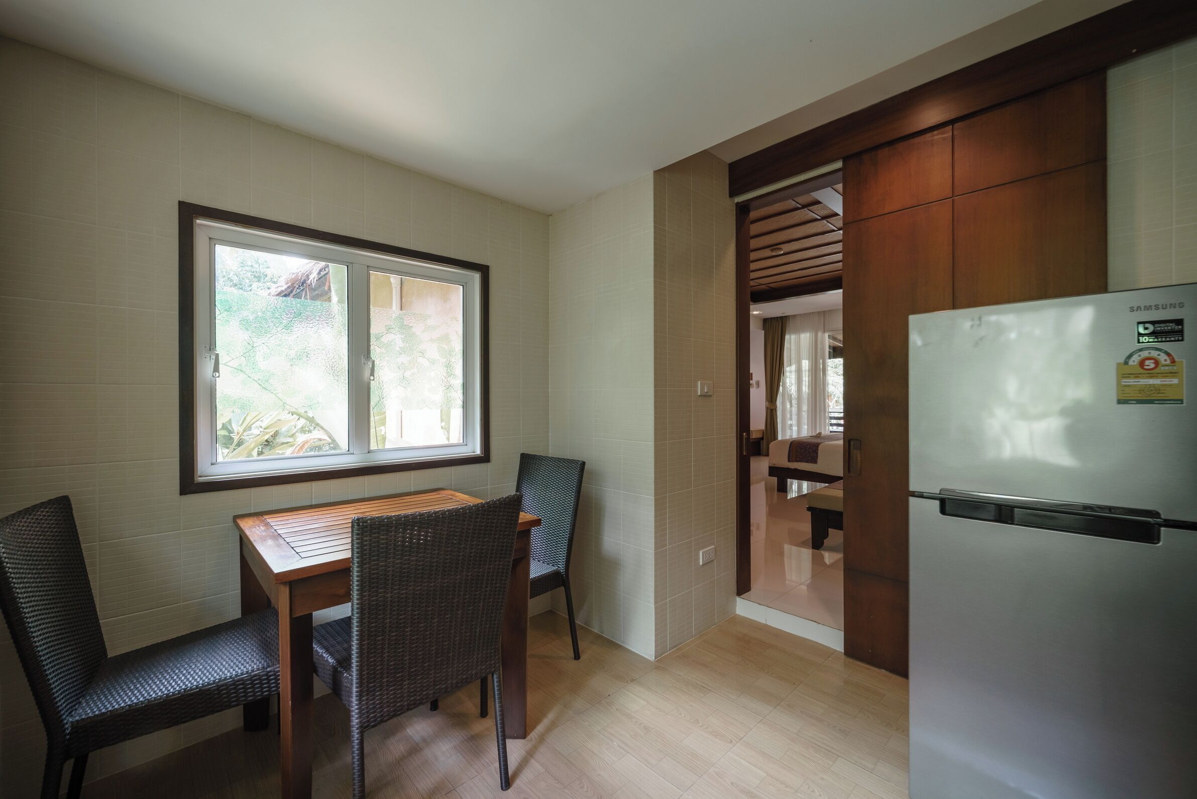 A compact kitchen with a dining table, chairs, a refrigerator, and a window providing natural light.