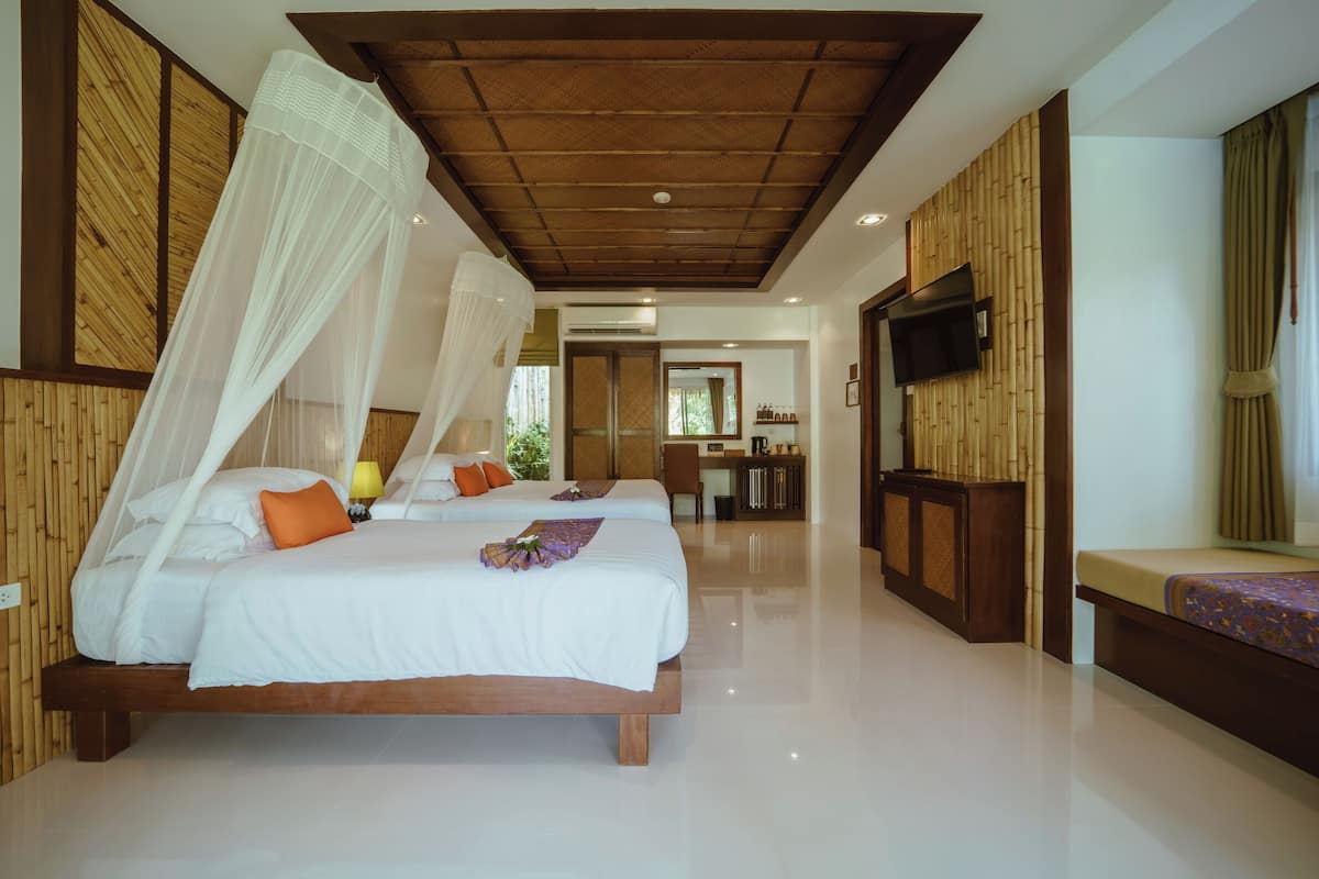 Habitación de hotel con dos camas, un televisor y un baño a la vista.