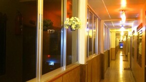 A hotel corridor with wooden paneling, large windows, and a hanging flower arrangement. - Aonang Grand Inn (Krabi)