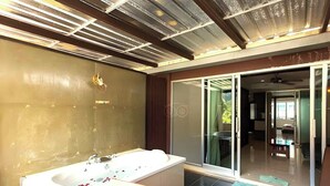Un baño moderno con una bañera grande, ducha y puerta de vidrio que da a un balcón.