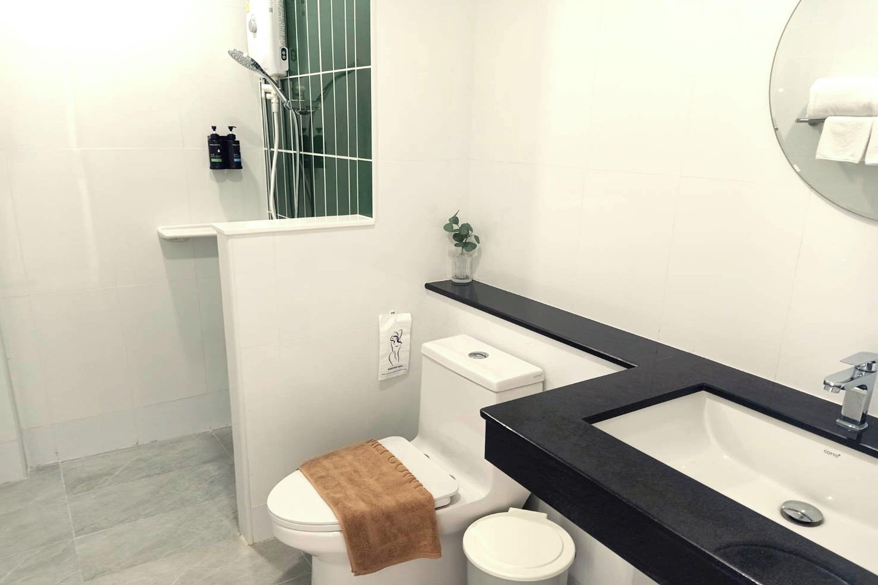 A modern bathroom with a white toilet, a black sink, and a shower area.