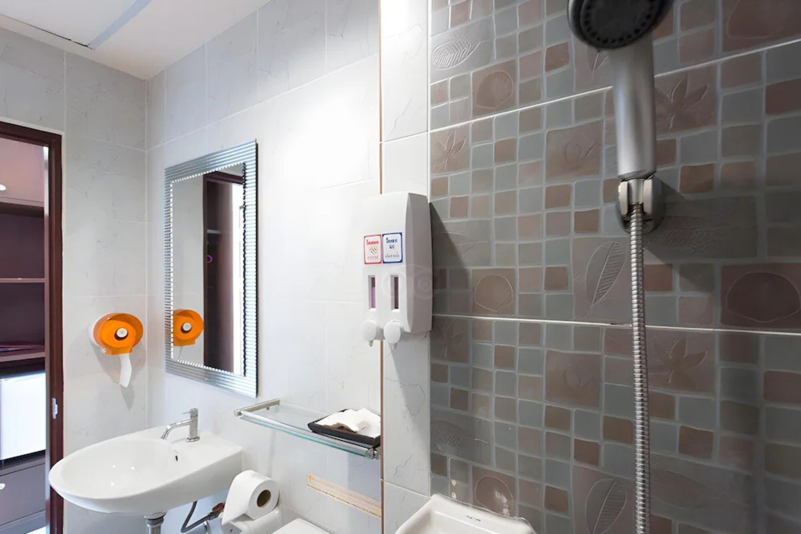 A bathroom with a sink, mirror, toilet, and shower.