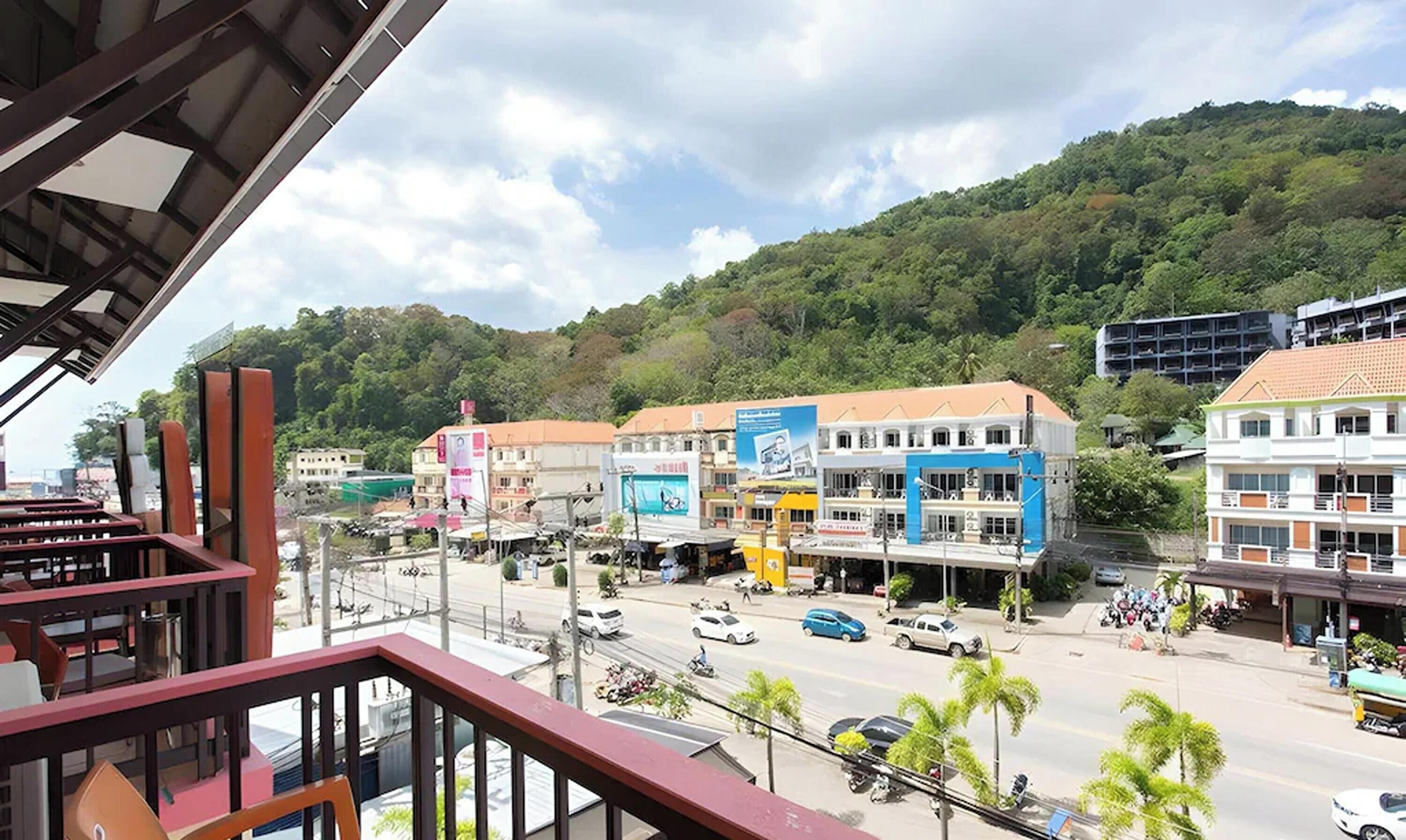 A street view with buildings, vehicles, and a hilly background.