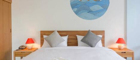 A hotel room with a neatly made bed, two bedside lamps, a wooden headboard, and a wall decoration of a boat on water.
