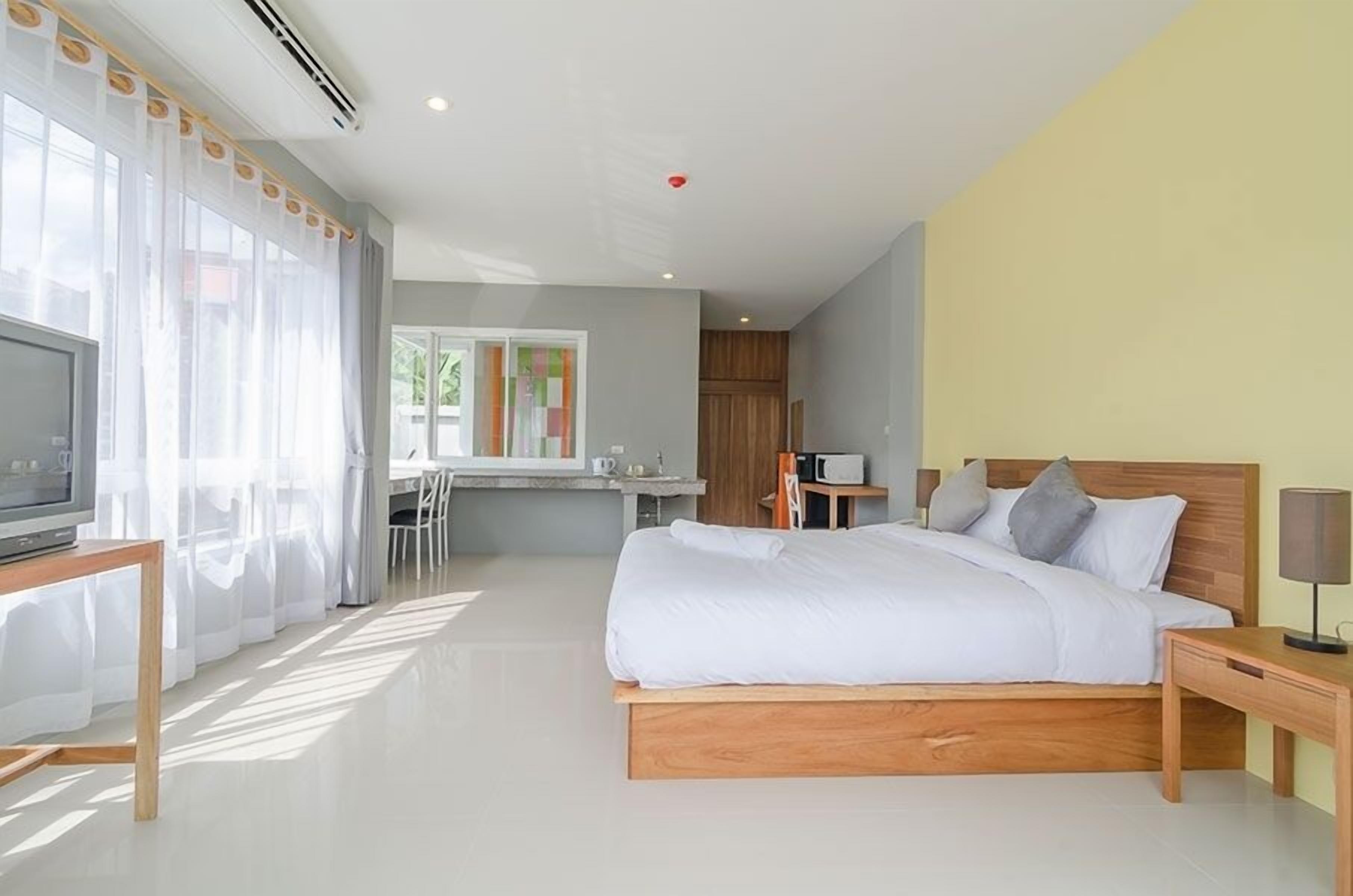 Une chambre d’hôtel moderne avec un grand lit, une table de chevet et un téléviseur posé sur un meuble en bois.