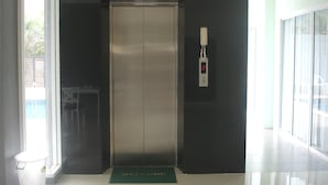 A modern elevator with a digital display, a welcome mat, and a glass door. - Aonang Miti Resort (Krabi)