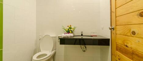 A small bathroom with a white toilet, a black sink, and a wooden door.