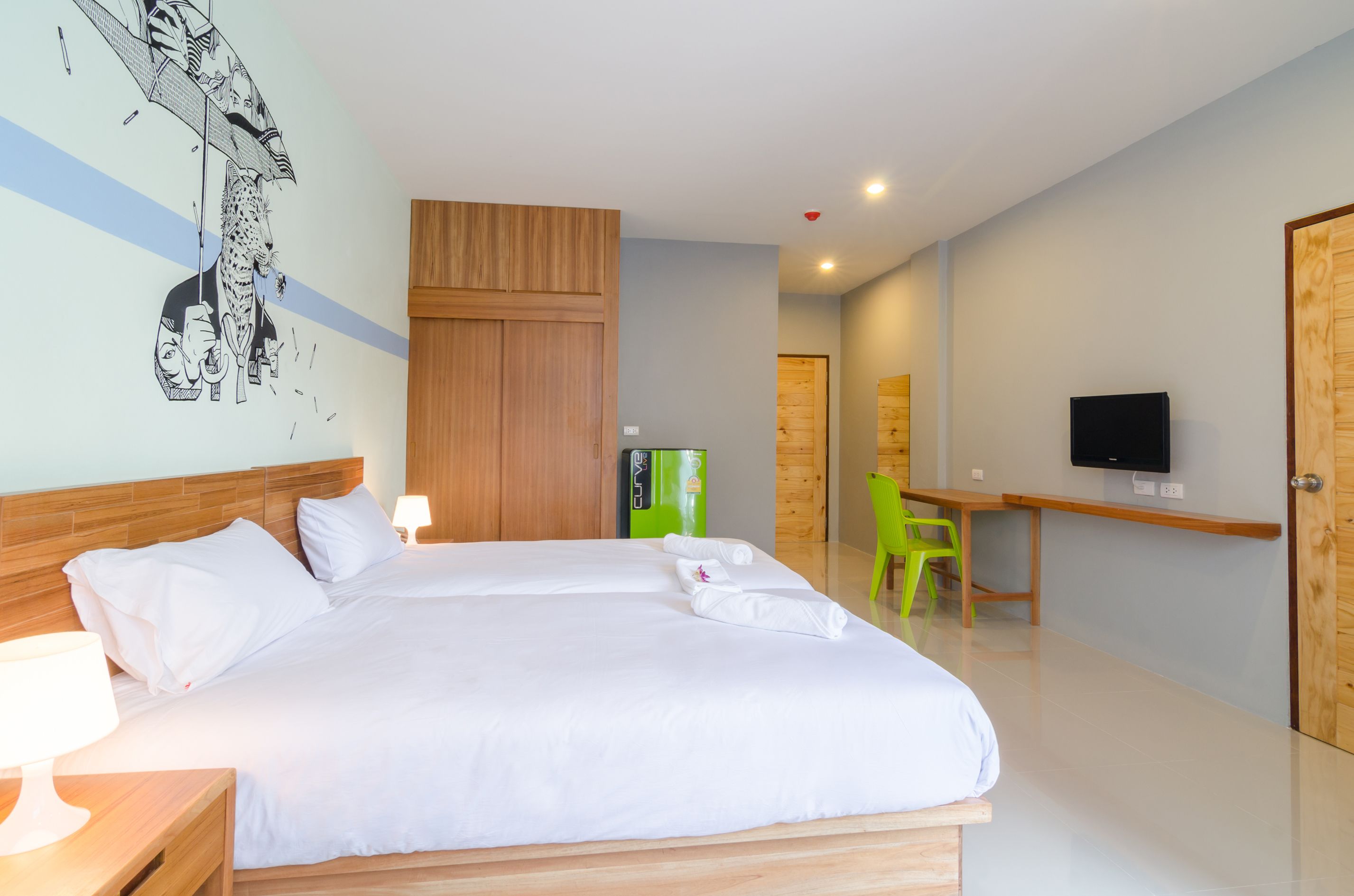 Una habitación de hotel con una cama grande, un escritorio, un televisor y una silla verde.