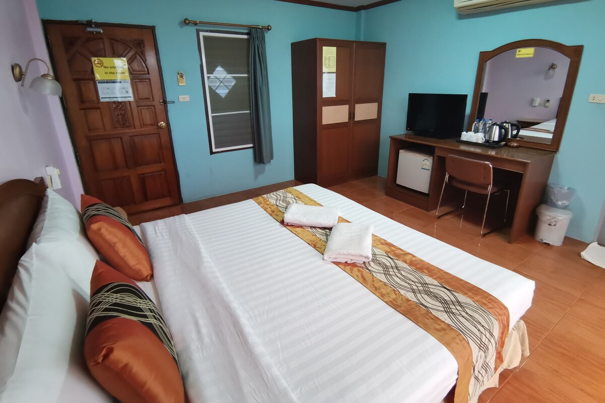 A hotel room with a bed, a desk, a television, and a wardrobe.