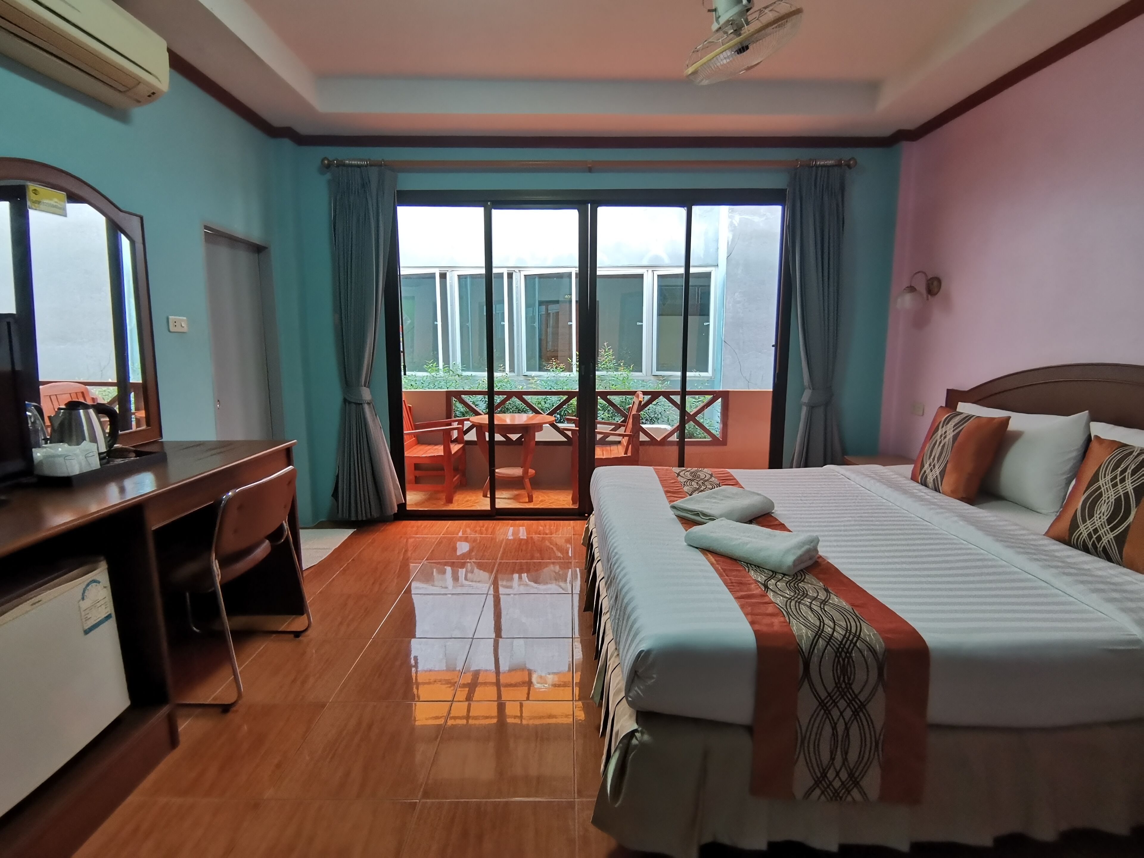 Ein Hotelzimmer mit Bett, Schreibtisch und einem Balkon mit Tisch und Stühlen.