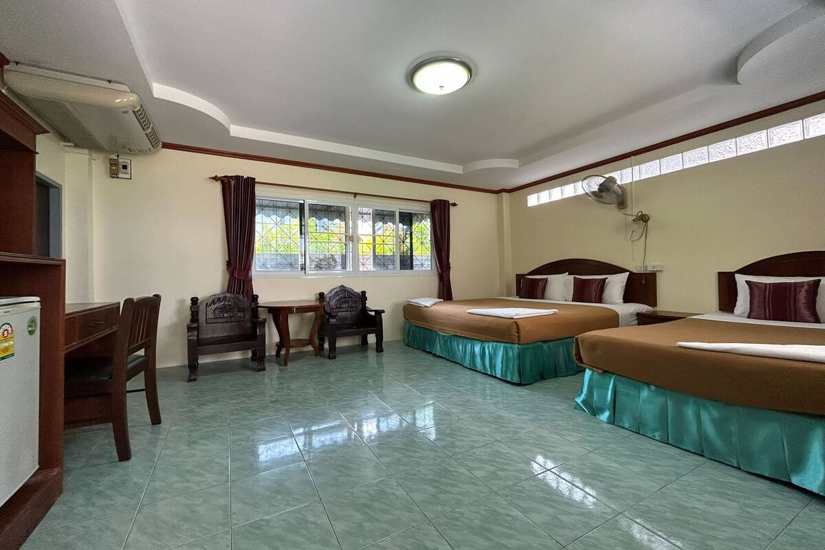 A hotel room with two beds, a desk, a chair, and a window with curtains.