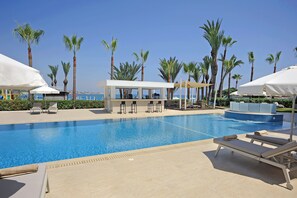 Un espace piscine équipé de chaises longues, de parasols et d’un bar.