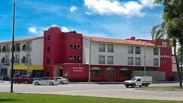 Un hotel con fachada roja y blanca, varias ventanas y techo plano.