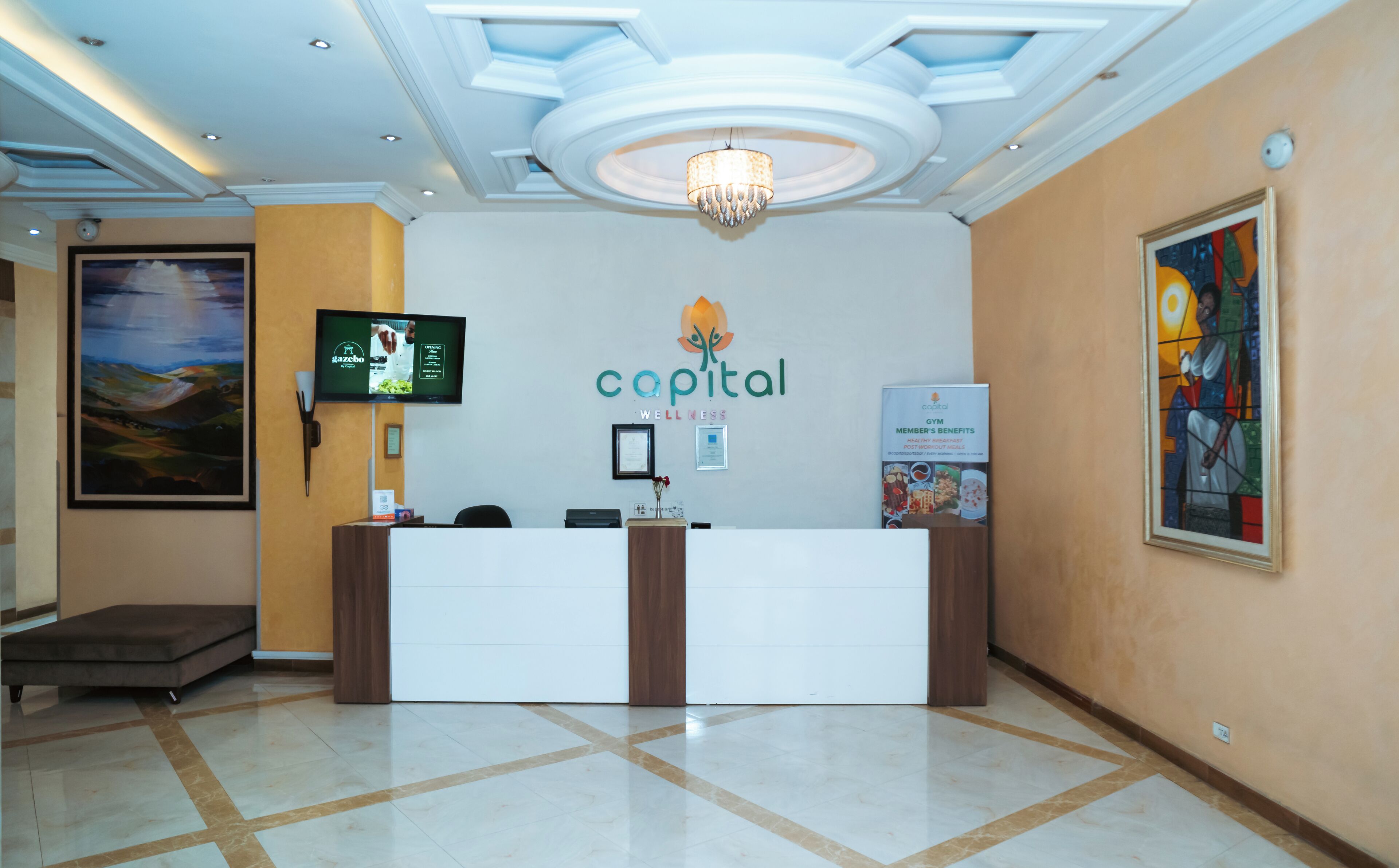 A reception desk with a logo, a television, and a framed artwork on the wall.