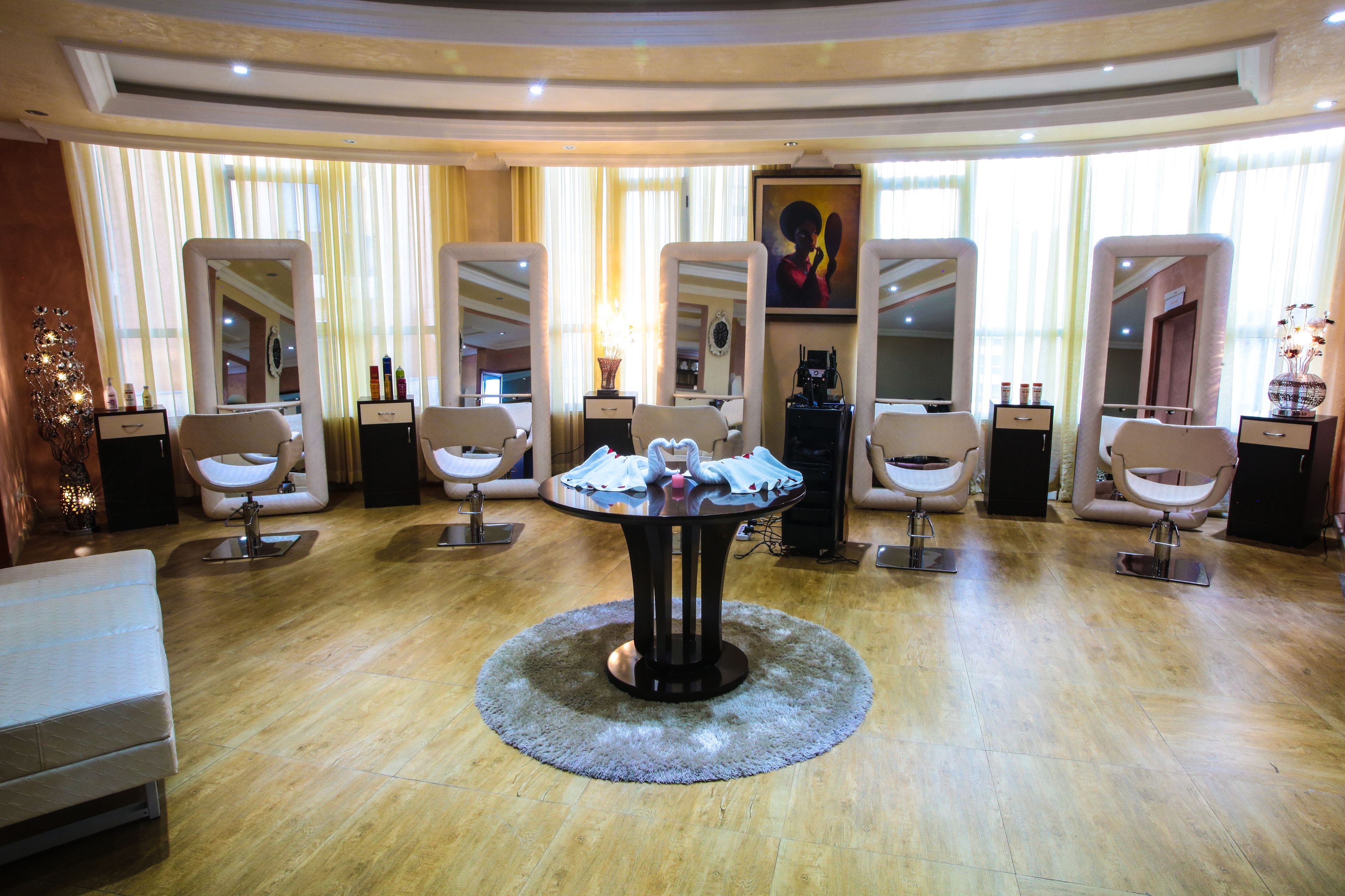 A salon with a central round table, multiple mirrors, and a few chairs.