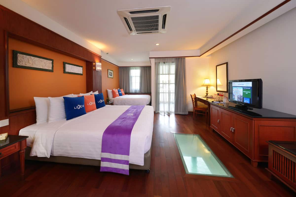 A hotel room with a large bed, a television, a desk, and a window.