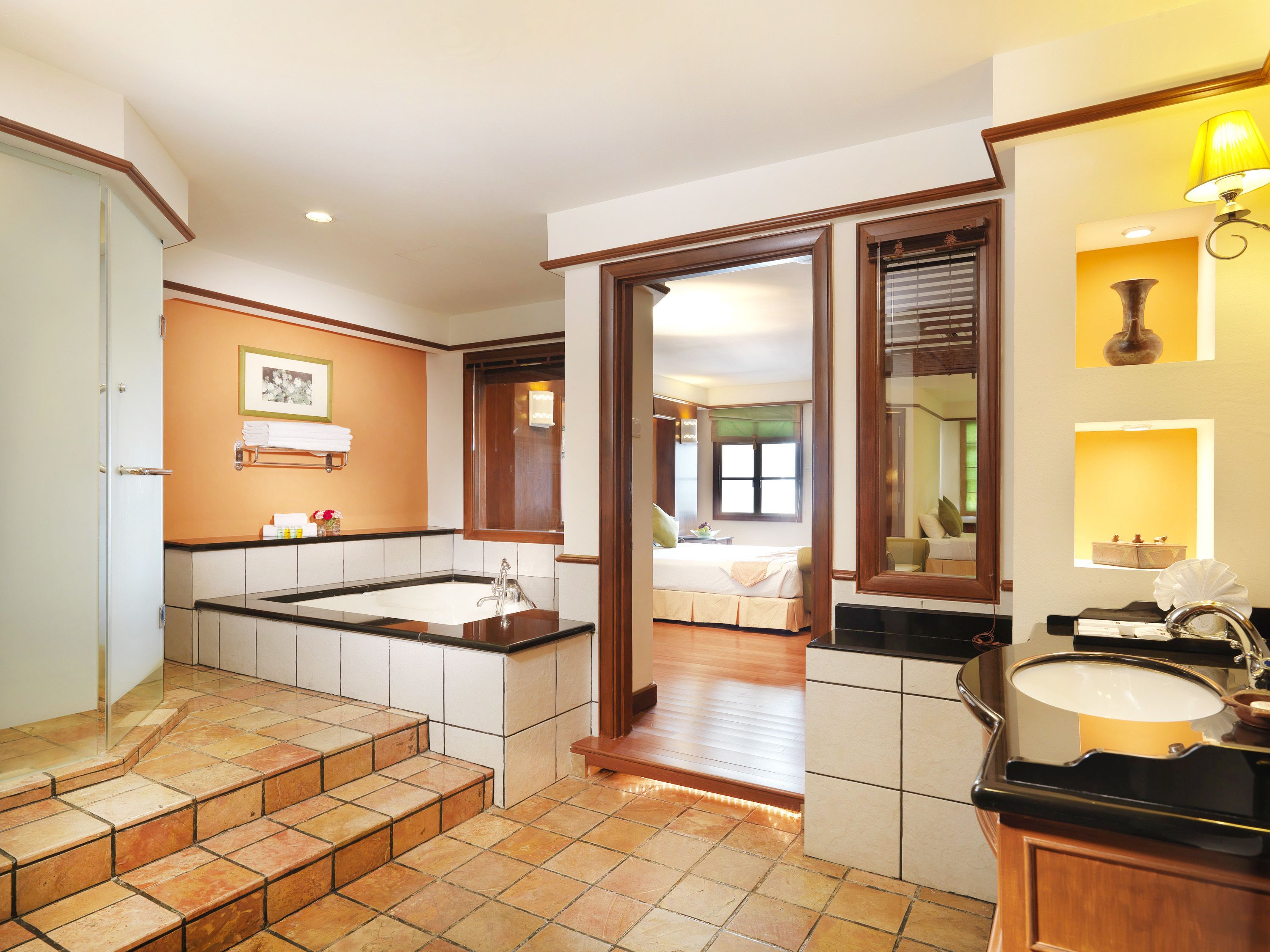 A hotel bathroom with a large bathtub, a sink, and a mirror.