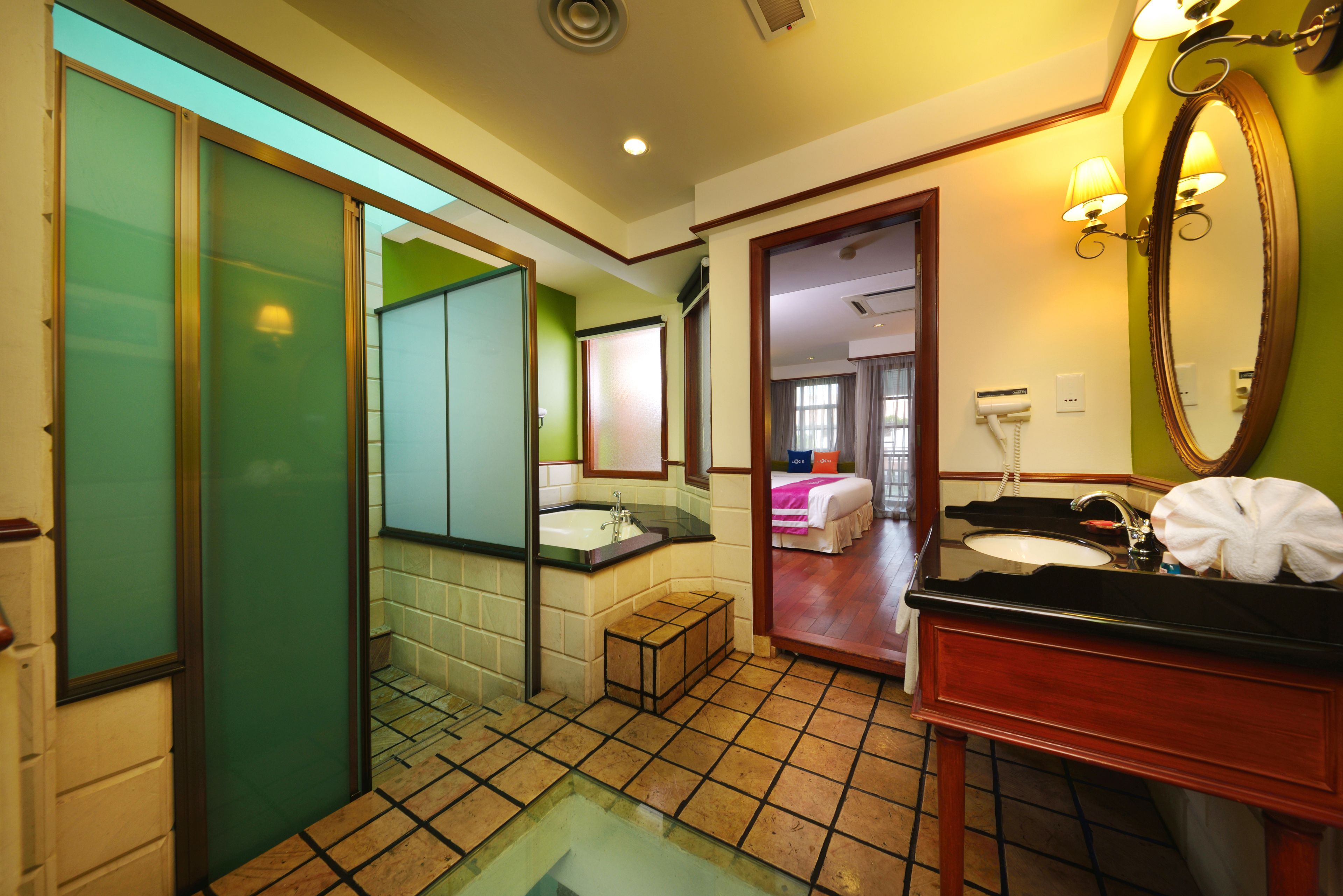 Une salle de bain d’hôtel avec une douche en verre, un lavabo avec un meuble-vasque, un miroir et une serviette accrochée au mur.
